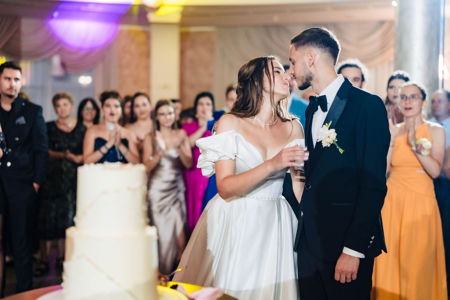 Wedding reception party scene with guests dancing under colorful lighting.