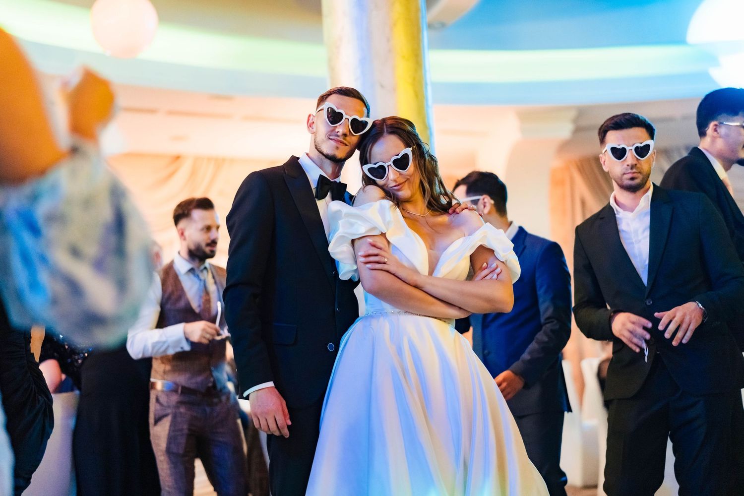 Wedding guests in formal attire mingle and dance at an outdoor reception celebration.