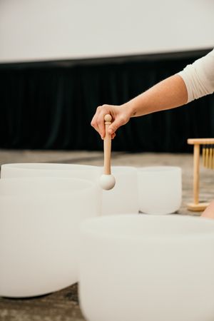 A hand gently drops a ping pong ball onto a white surface in a minimalist composition.