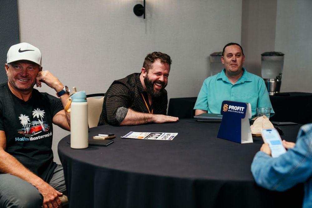 People seated at a black table during a meet and greet session with drinks and conversation.