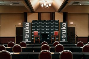 Large conference room with rows of burgundy chairs and chandeliers illuminating the space from above.