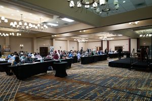 A panoramic view of a large conference room with rows of chairs and tables set up for a business meeting.