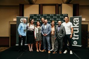 Group of professionals gather for a networking event in a modern conference space with dark walls and signage.