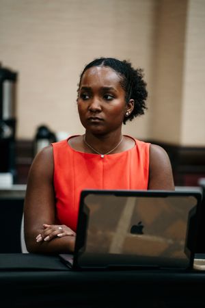 A series of shots showing someone in a coral sleeveless top sitting at a desk with a laptop.