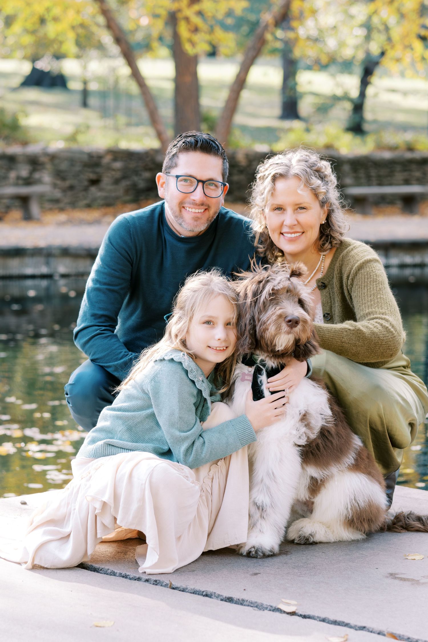 Coordinated family outfit set in soft blue and cream tones with dresses, sweaters, pants and matching accessories laid flat.