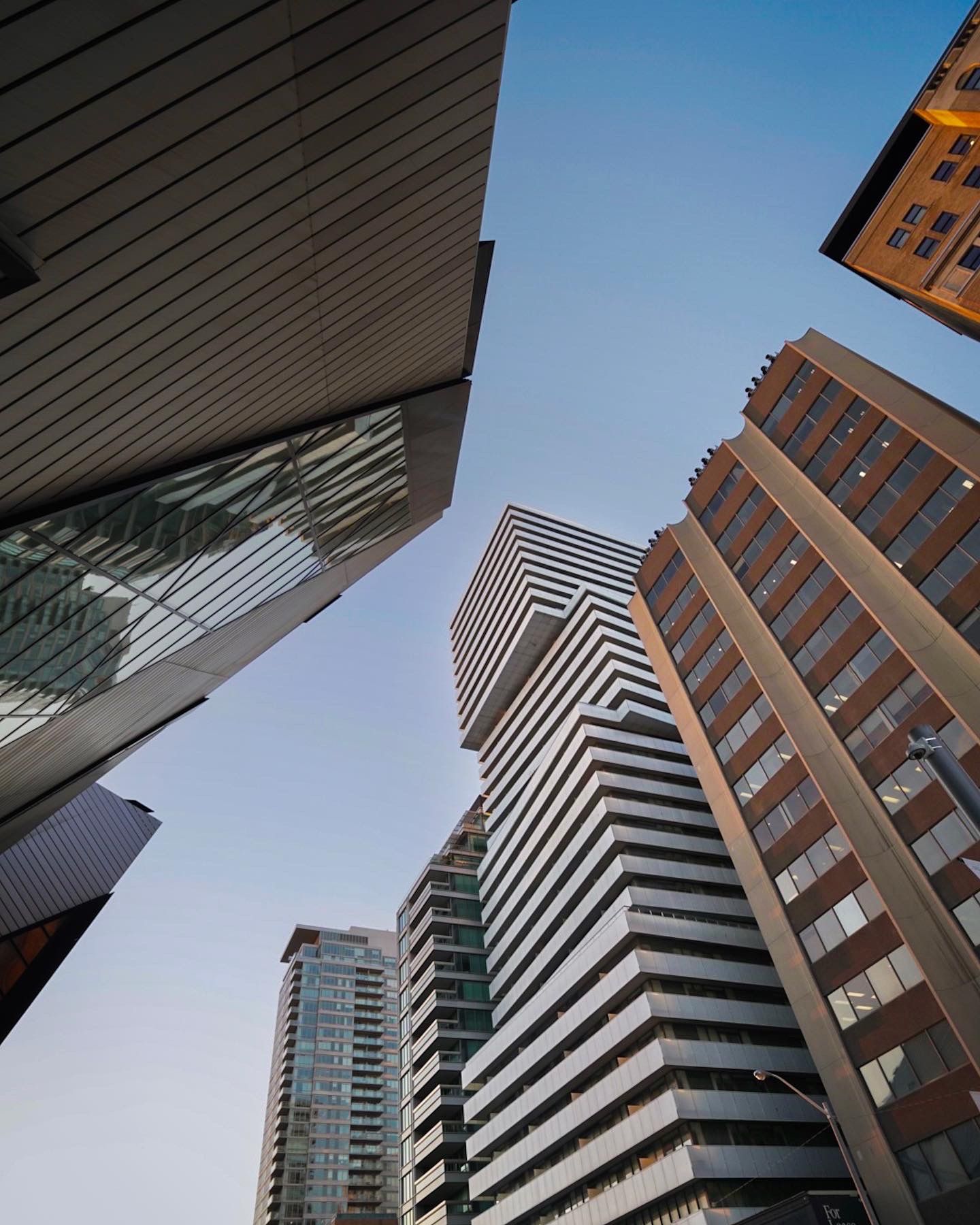 Modern urban architecture with striped building facades shot from below against blue sky.