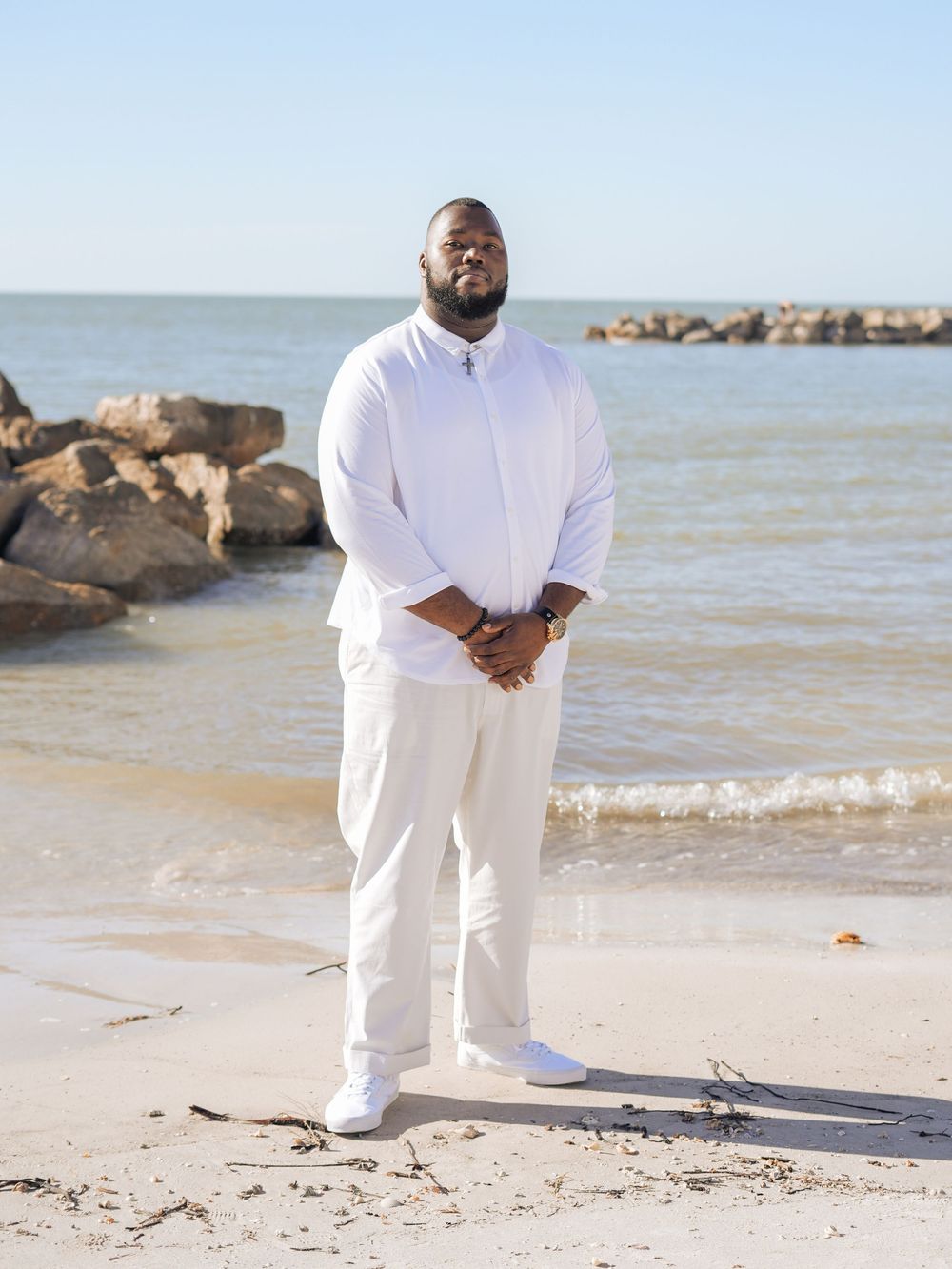 A collection of photos showing a person in white attire standing on a tranquil beach near rock formations and water.