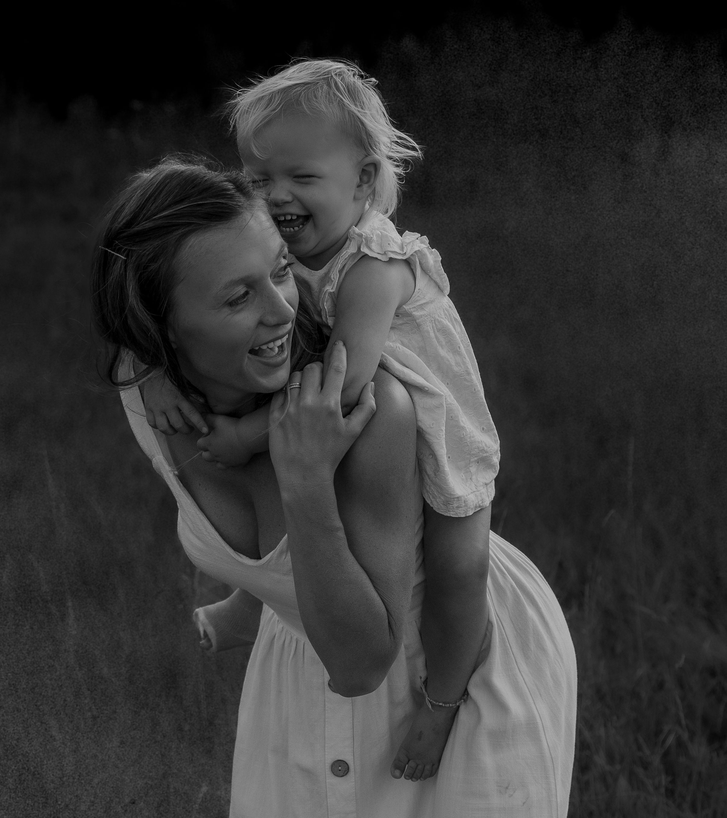 A joyful black and white portrait capturing a tender moment of shared laughter and connection outdoors.