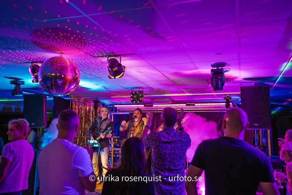 A purple and blue illuminated nightclub interior with vibrant neon lighting and silhouettes of people dancing.