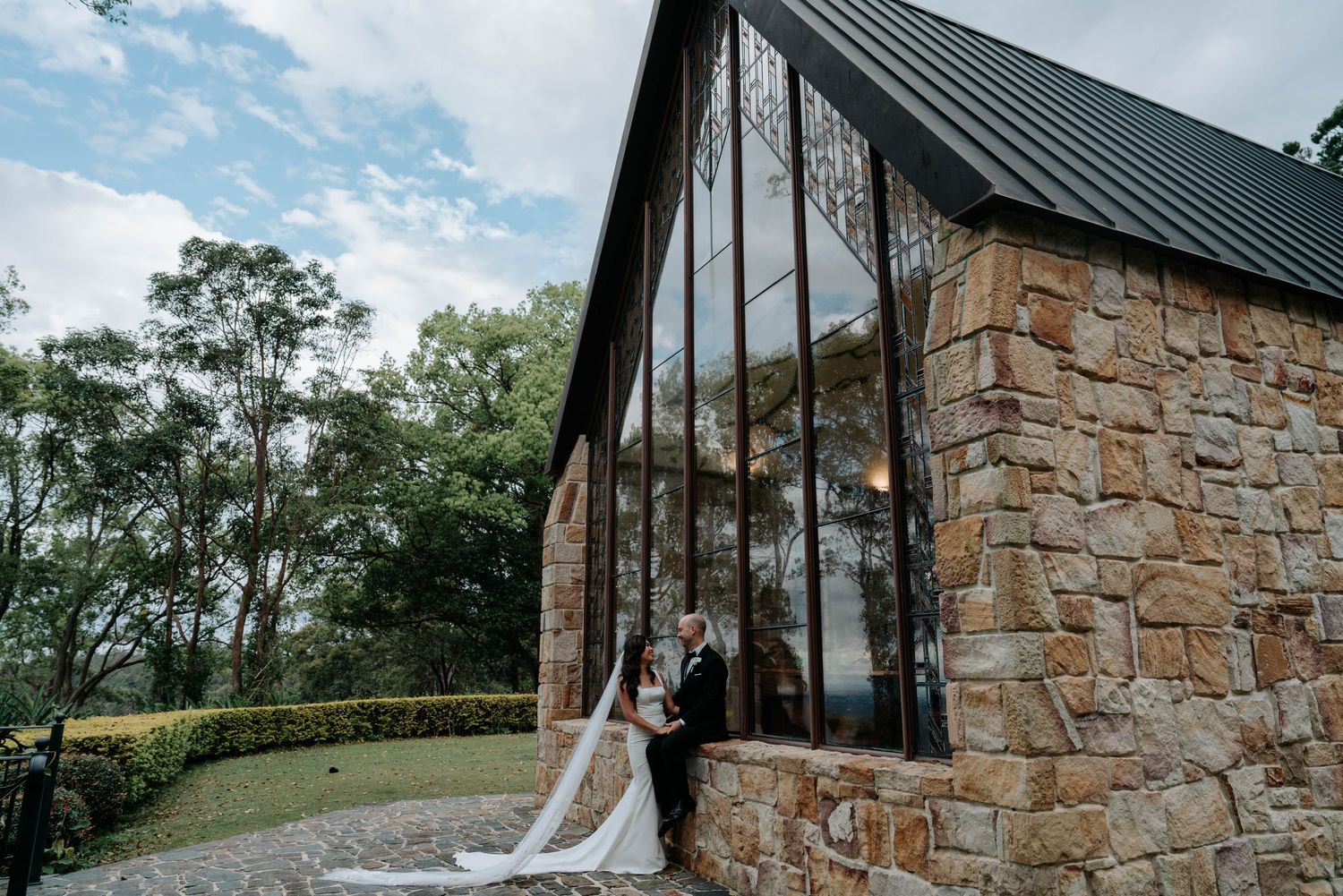 A rustic stone and wood A-frame wedding chapel nestled in a scenic outdoor setting with elegant white draping.