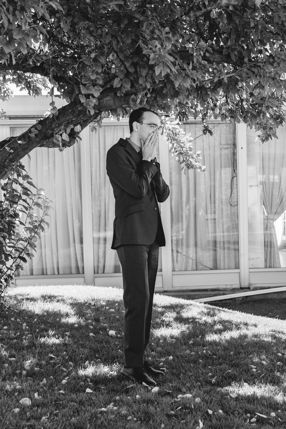 Black and white wedding photos showing a couple's intimate moment beneath branches of a tree.