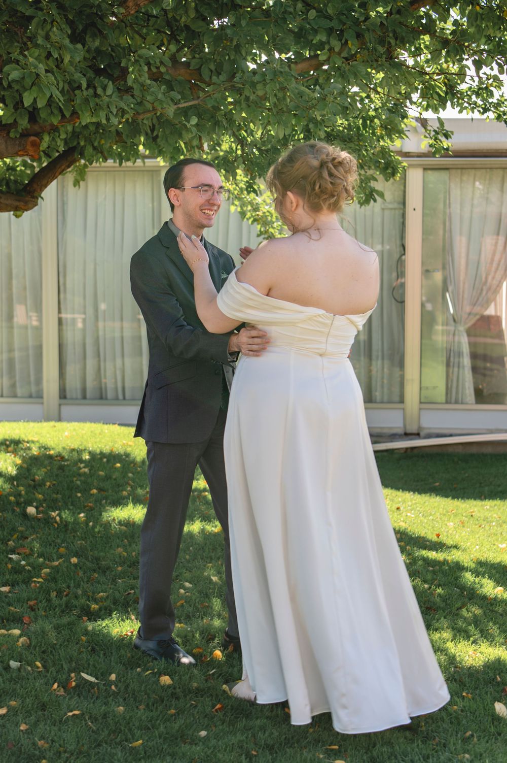 A couple dances together in a backyard garden setting wearing formal wedding attire.