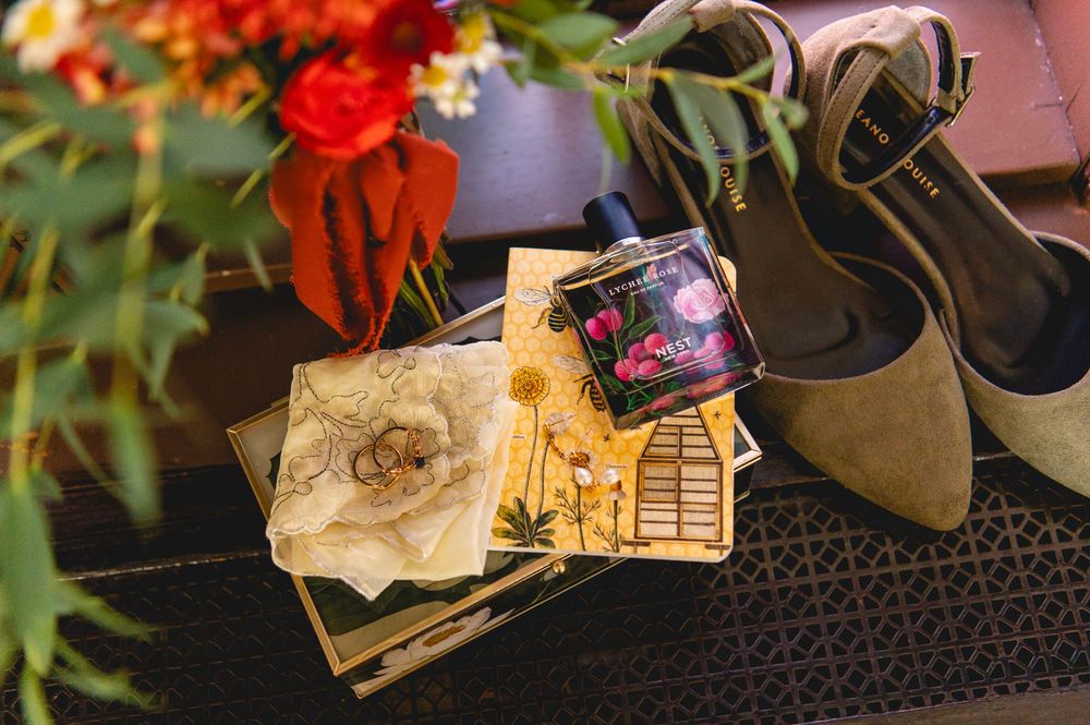 A collection of personal items including shoes, money, and a keyboard arranged on a dark surface with red flowers visible.