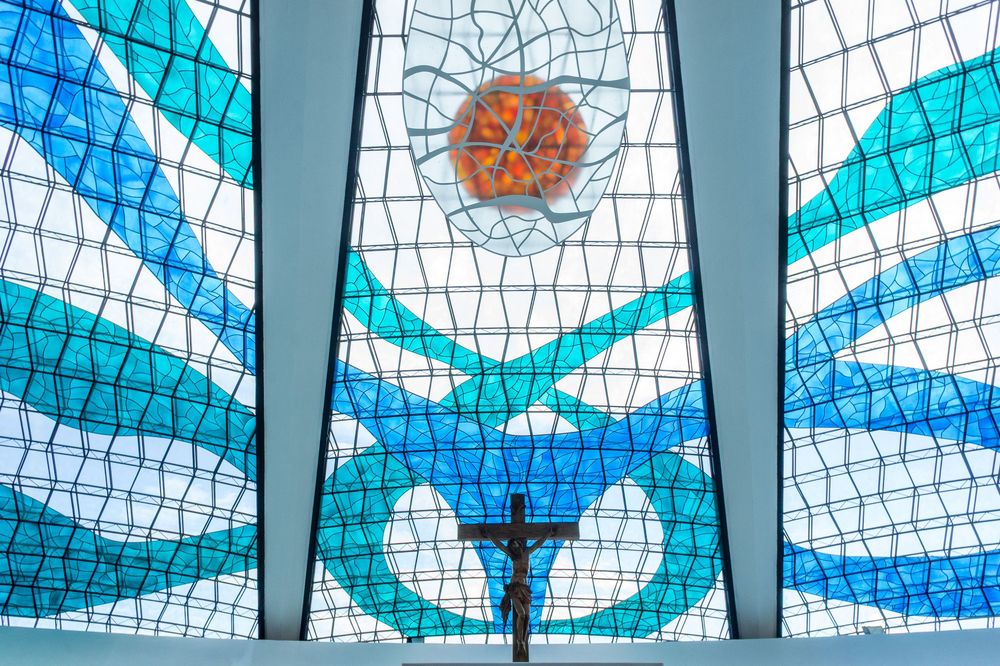 Stained glass mosaic ceiling with geometric patterns in blue and turquoise tones creates an abstract kaleidoscope effect.