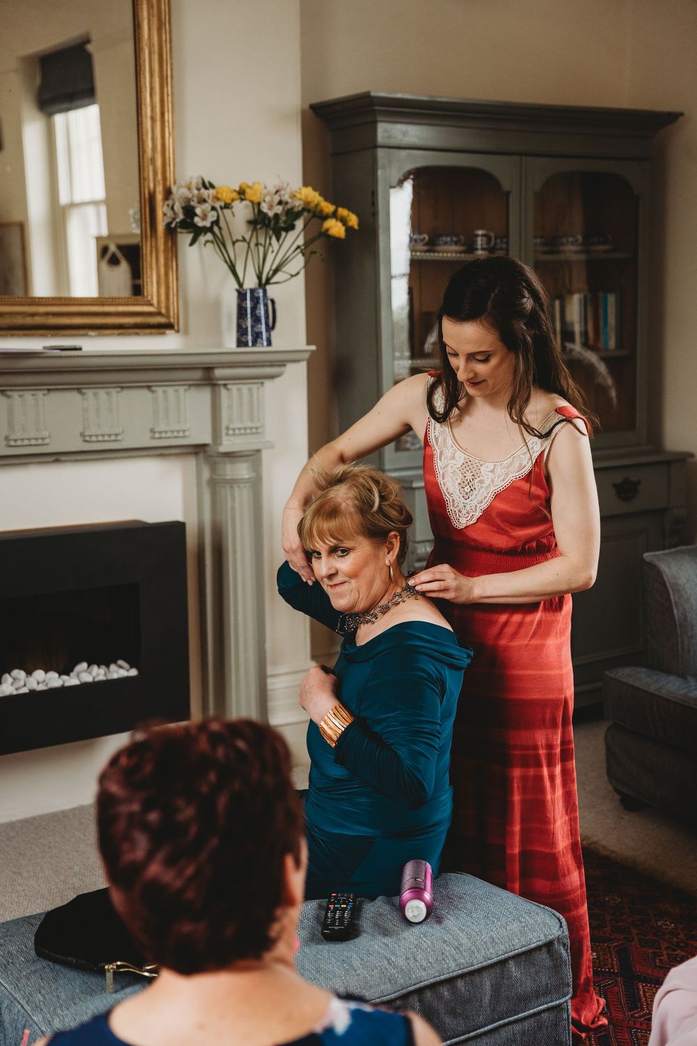Wedding preparation scene in a cozy living room with bridesmaids helping with final touches.