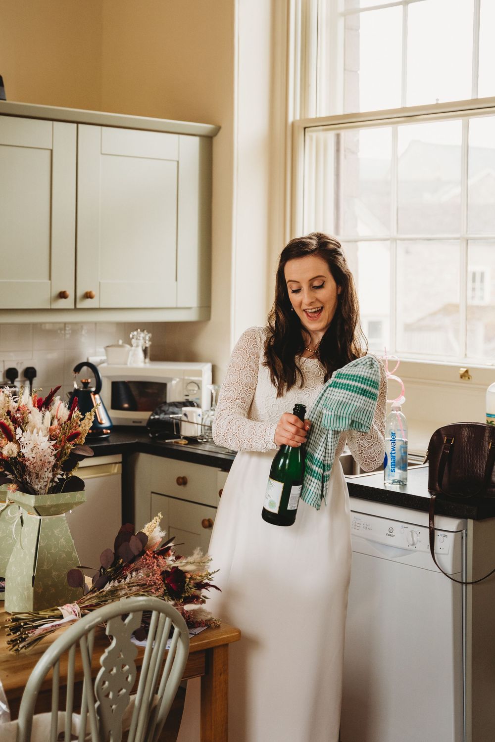 A sequence of joyful moments in a sunlit kitchen during wedding preparations.