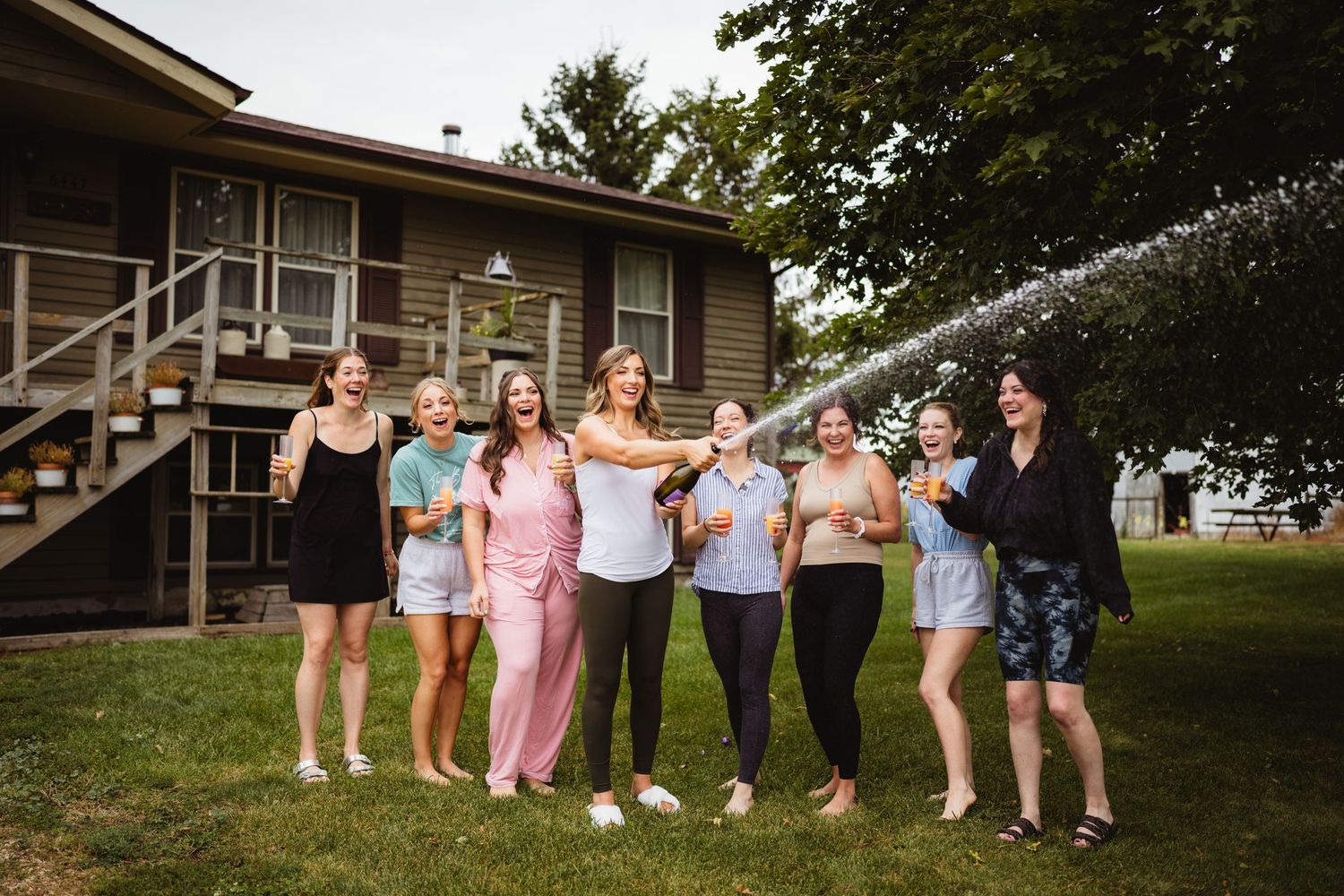 Wedding party enjoys candid moments in outdoor garden setting during summer celebration.
