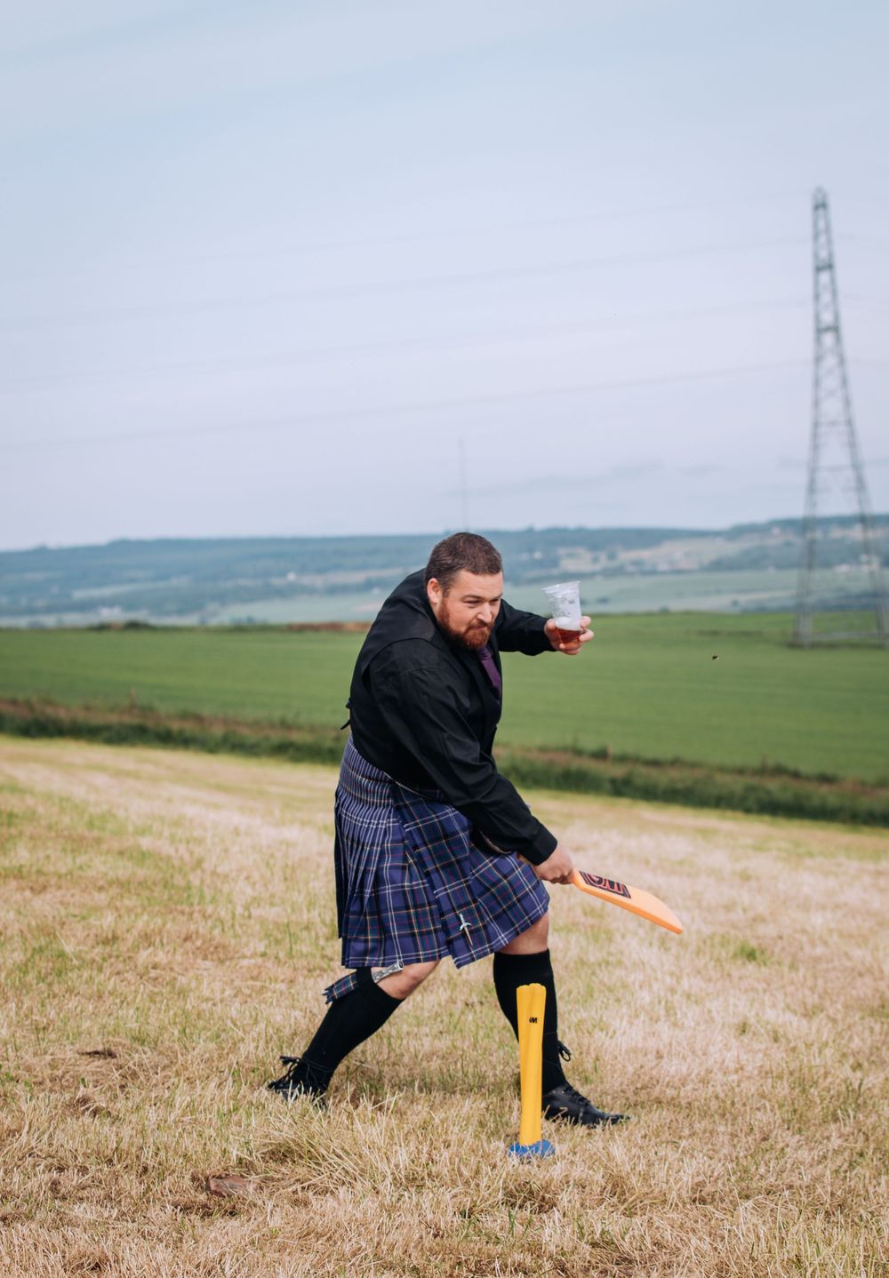A sequence of photos showing someone in a kilt performing a cricket bowling action on a grassy hillside.