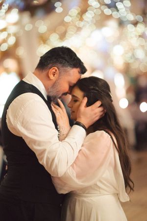 A romantic wedding moment captured with bokeh lights as couple shares an intimate embrace.
