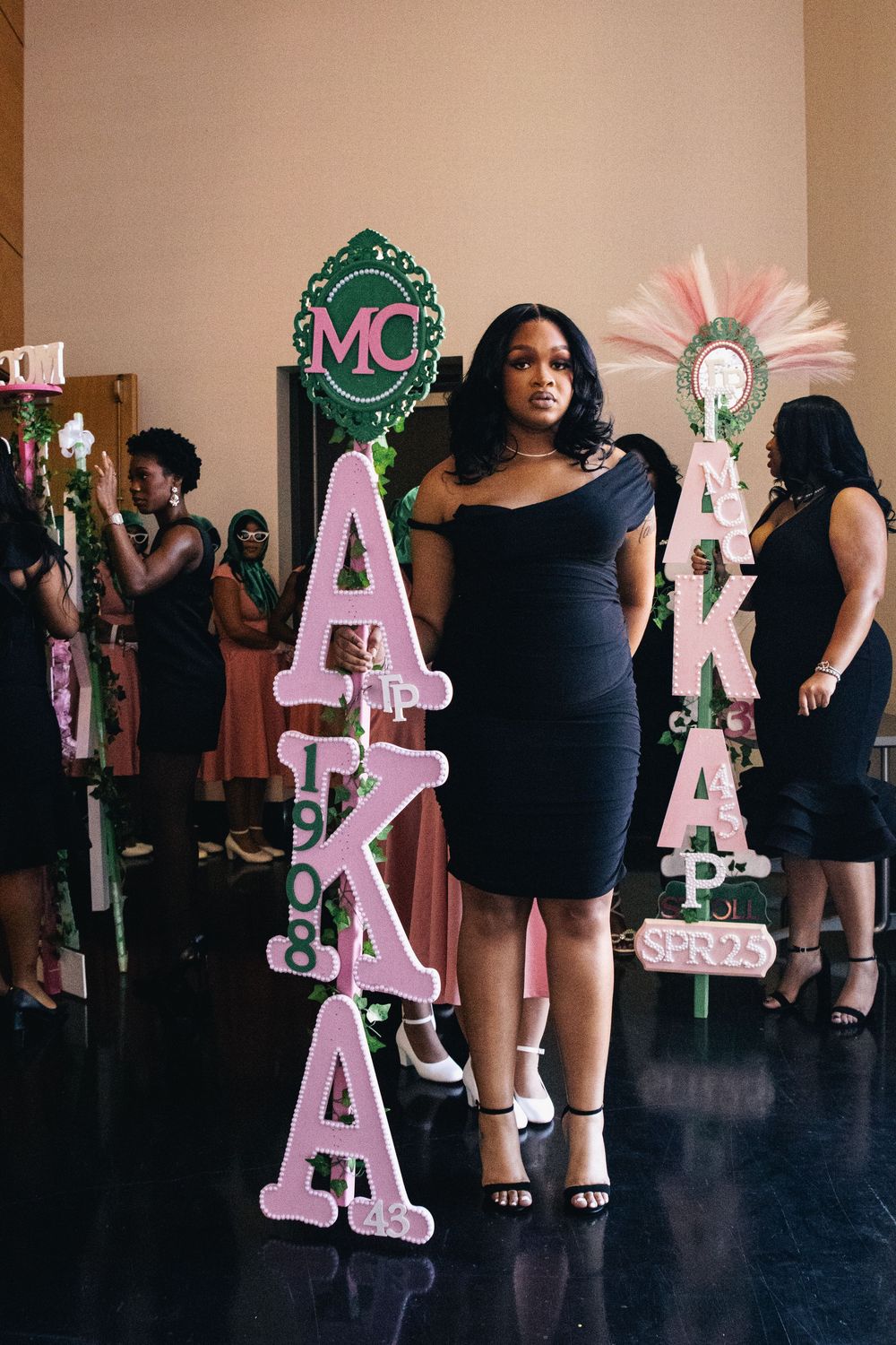 Pink decorative letters and props displayed at performance venue with black backdrop.