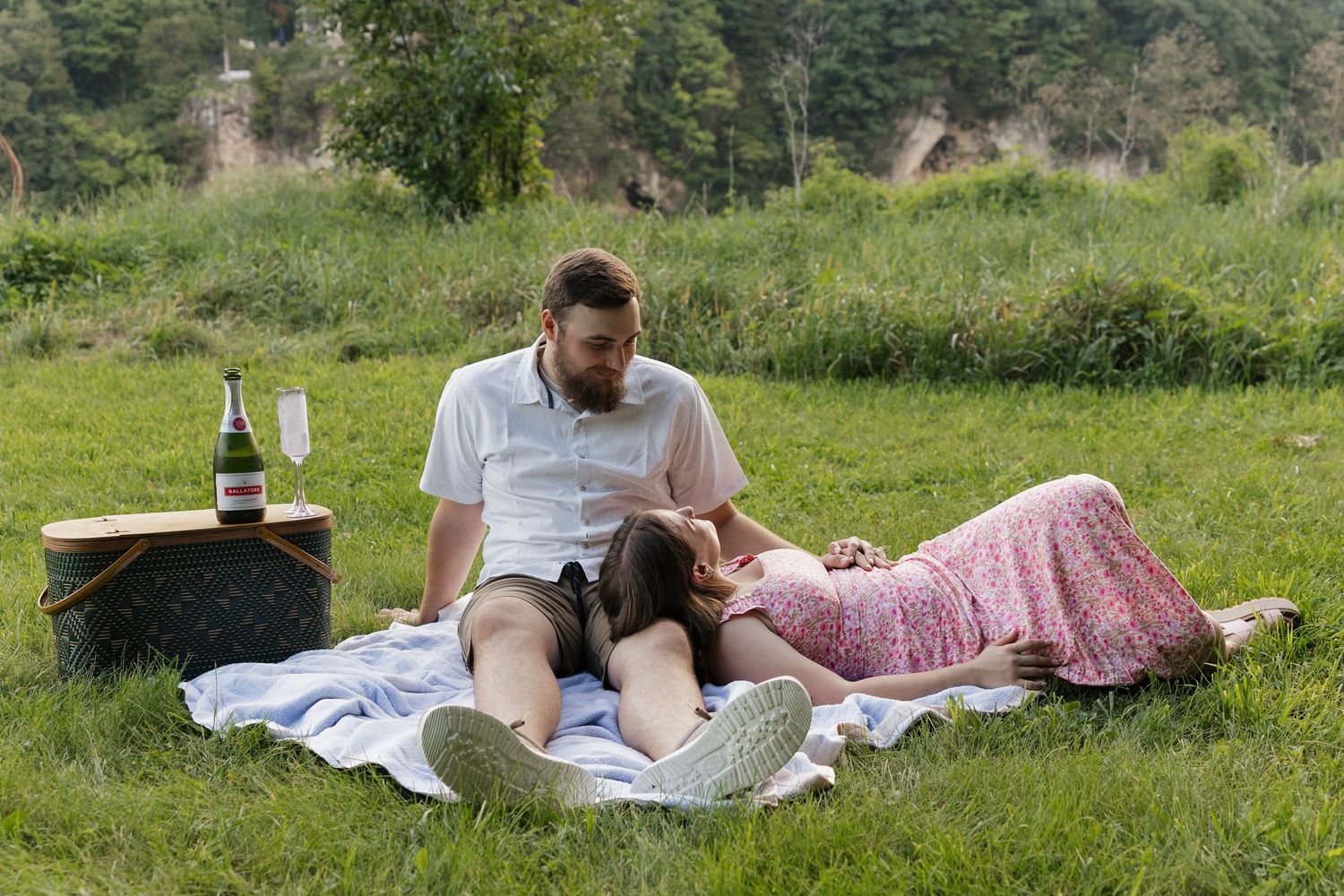 Two people relax on a blanket in a lush green meadow on a sunny summer day.