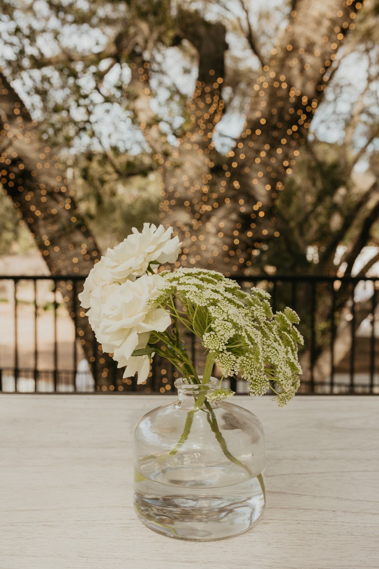 White carnation and green Queen Anne's lace flowers arranged in a clear glass vase on a light surface at The Oaks at Duncan Lane.