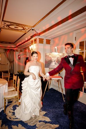 Wedding celebration in a decorated room with red accent lighting and white draping.