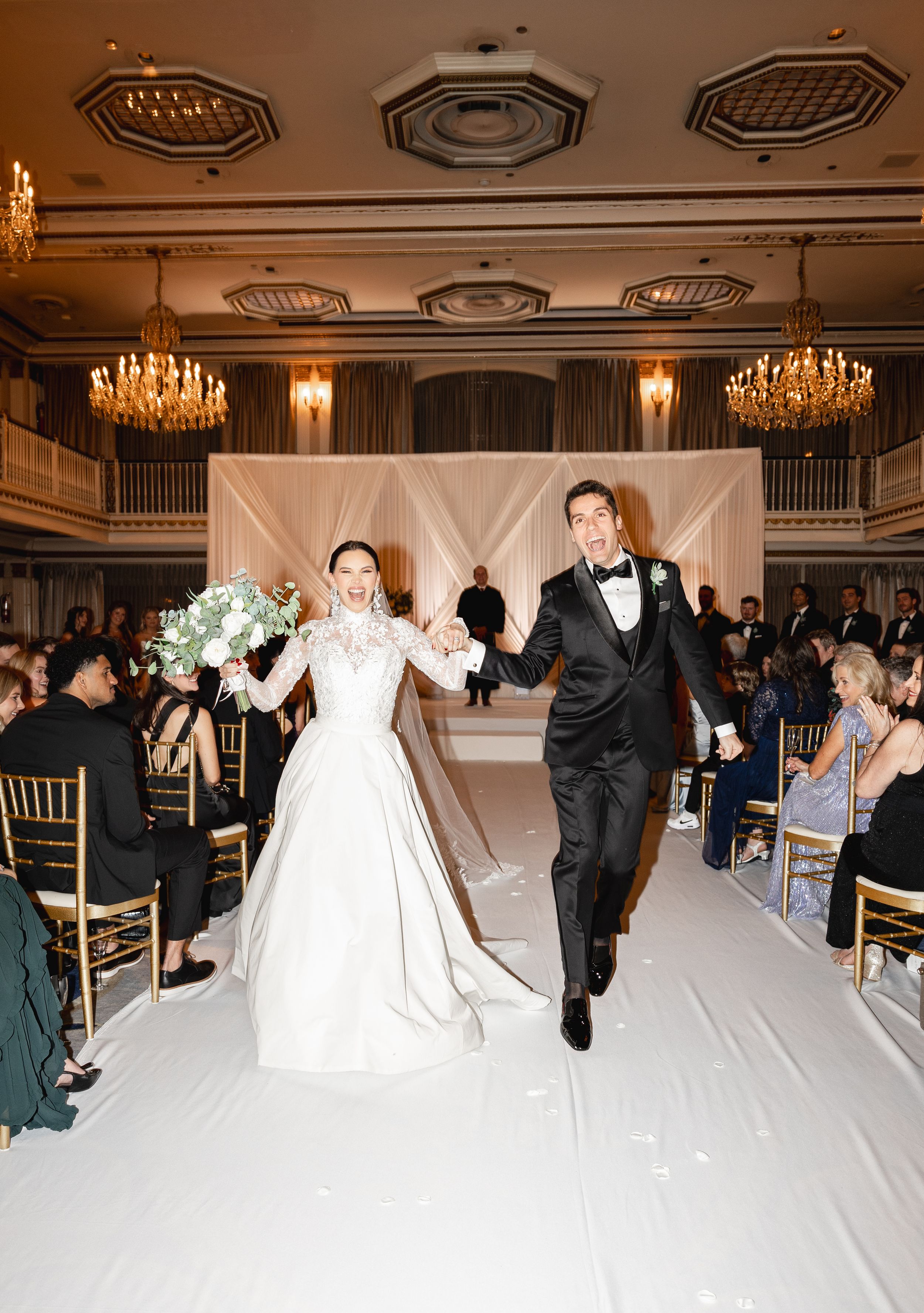Wedding ceremony in the Drake Hotel Chicago elegant ballroom with chandeliers and white draping showing moments of celebration.