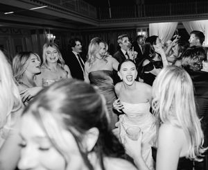 Black and white photo of wedding guests dancing and celebrating on the dance floor.