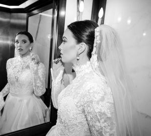 A collection of black and white photos showing close-up details of a bride in an elegant lace wedding gown and veil.