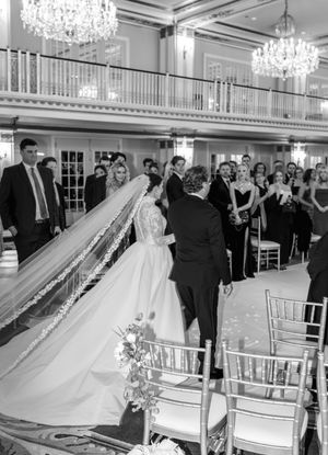 Elegant ballroom wedding reception with crystal chandeliers and white chairs.