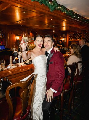 Wedding celebration at a dimly lit bar with guests in formal attire enjoying drinks and dancing.