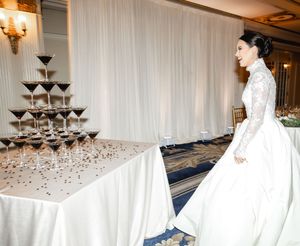 Wedding reception setup with champagne tower and white draping in an elegant ballroom.