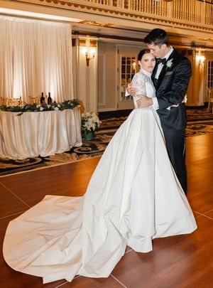 A romantic first dance moment in an elegant ballroom with draped decor and warm lighting.