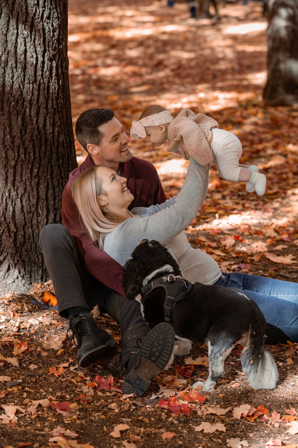 A couple relaxes on autumn leaves in a forest while enjoying hot beverages together.