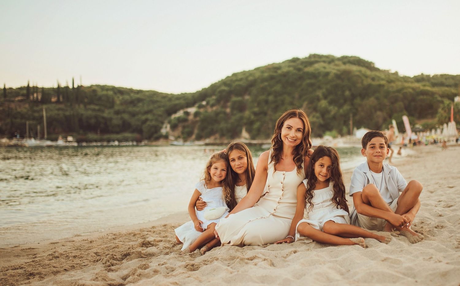 A group in white dresses gathers on a sunlit garden path during golden hour creating a warm and intimate moment.