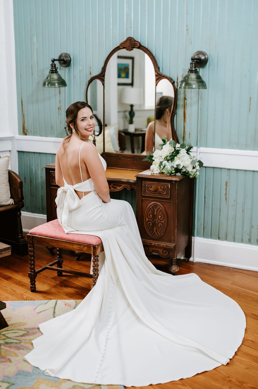 A bride in a flowing white wedding dress twirls and spins in a rustic room with blue walls and vintage furniture.