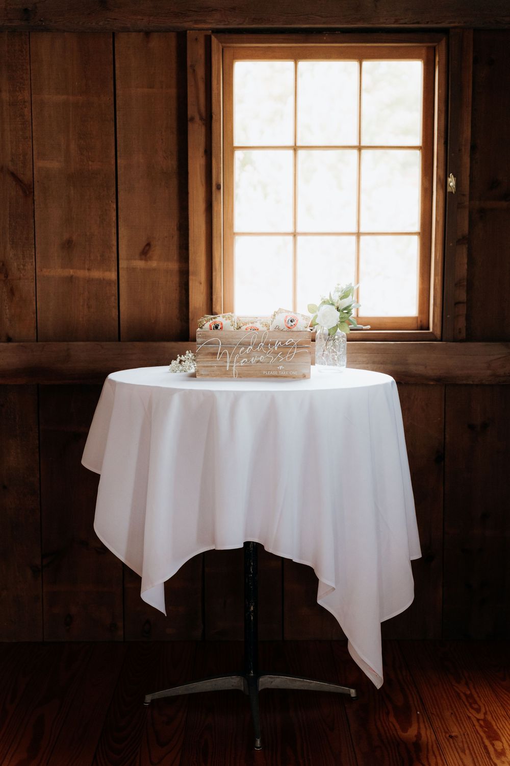 Rustic wooden room interior with white tablecloths and sunlight streaming through windows. Wedding reception. Traverse City, Garvey Farm.