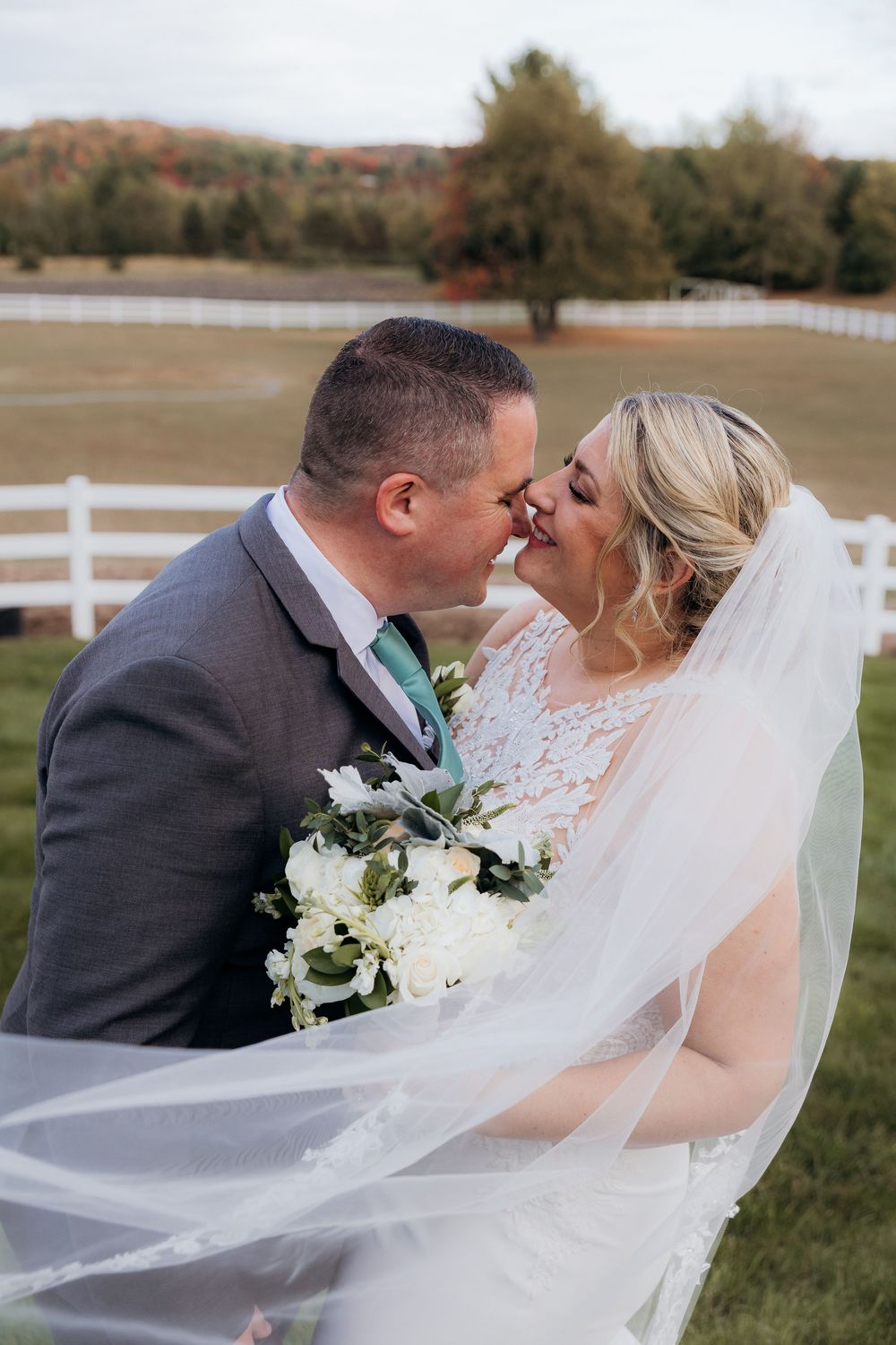 Romantic wedding portraits with flowing veil against autumn landscape.
