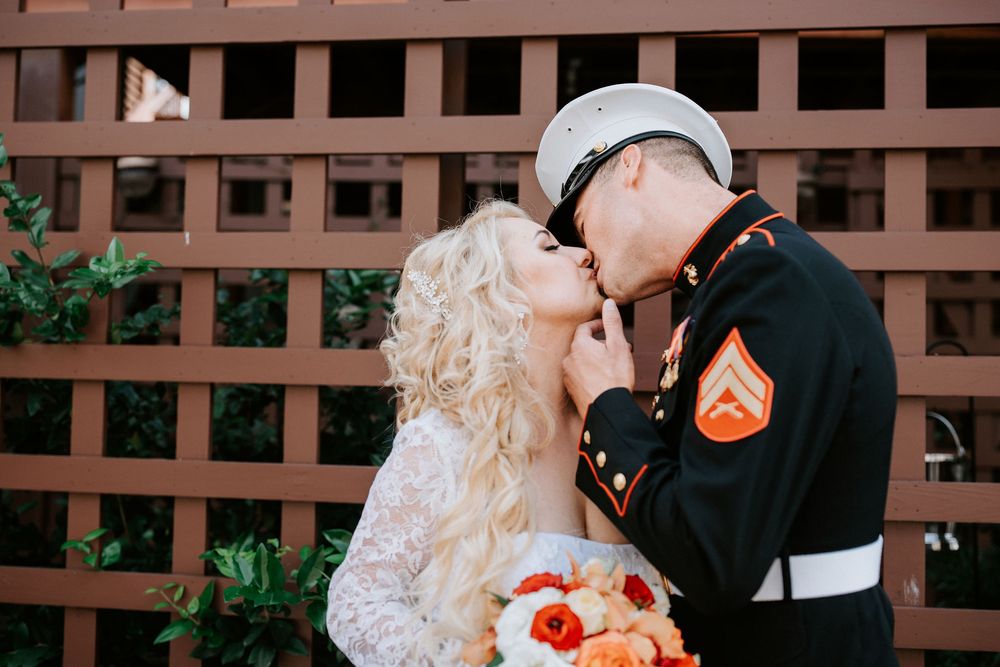 A bride and groom share an intimate moment during their wedding ceremony in front of a wooden lattice backdrop.