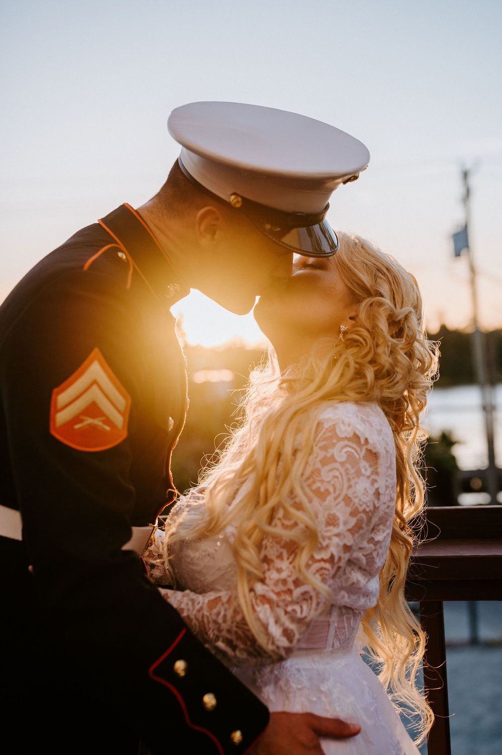 Silhouetted couple embracing at sunset with golden light streaming through their figures.