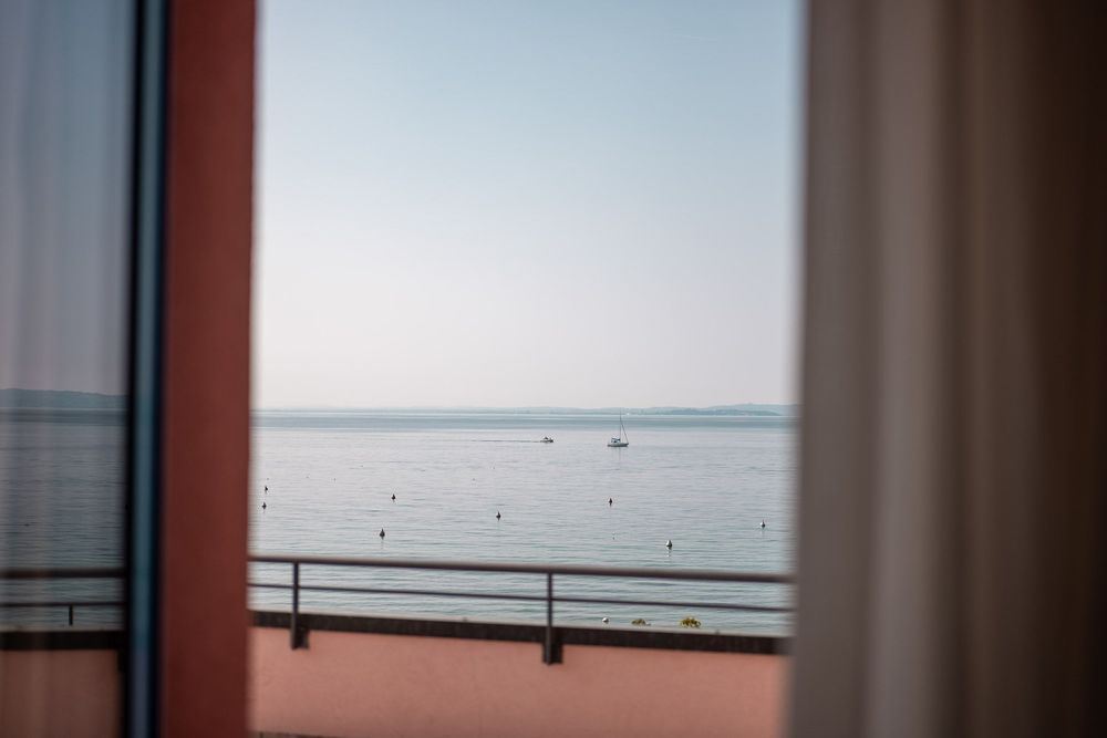 Blick aus dem Hotelzimmer auf den blauen Gardasee in Italien.