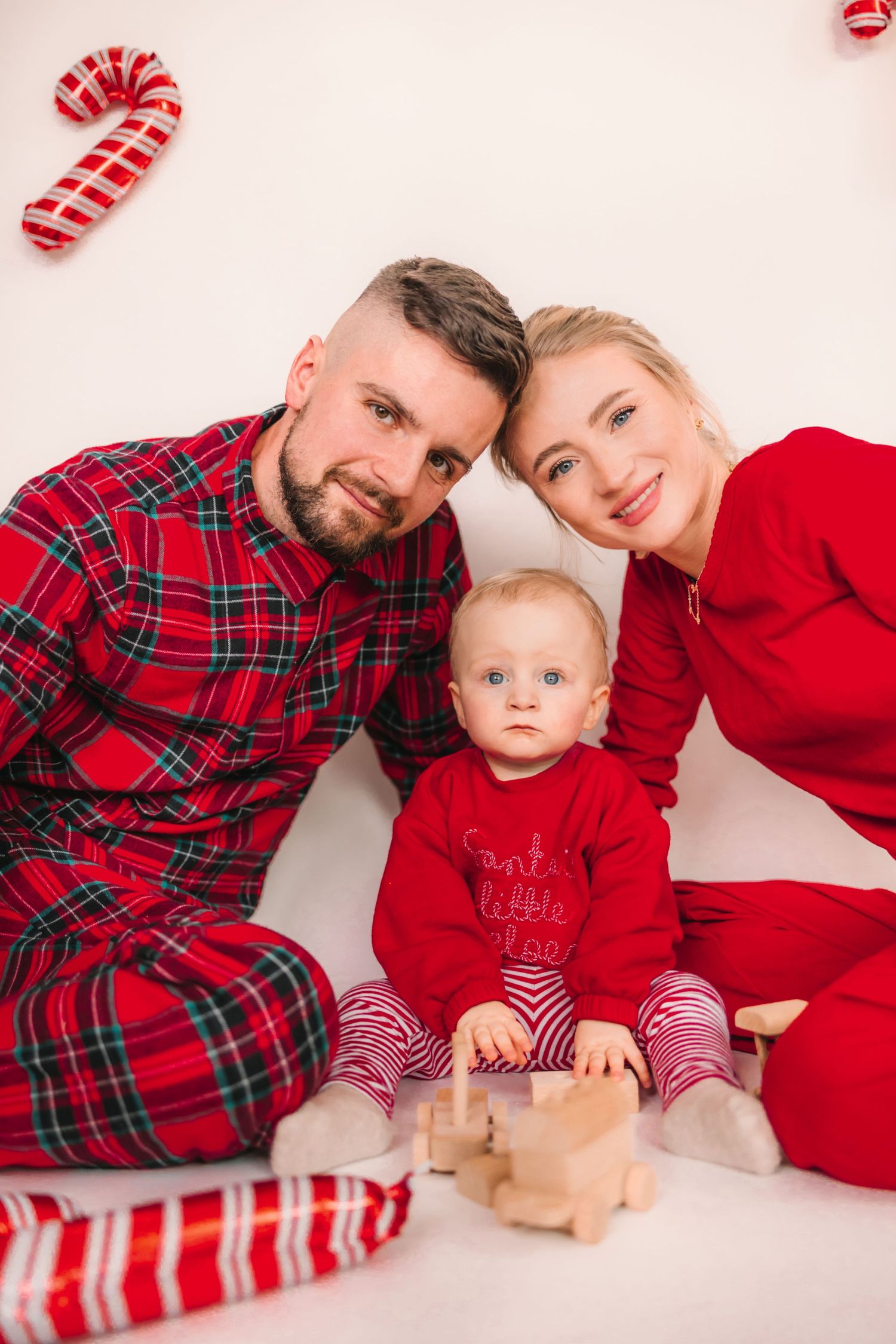 Šťastní rodičia s malým dieťatkom vo vianočných outfitoch, profesionálne vianočné momentky z ateliéru Foxography pre klientov zo Žiliny.