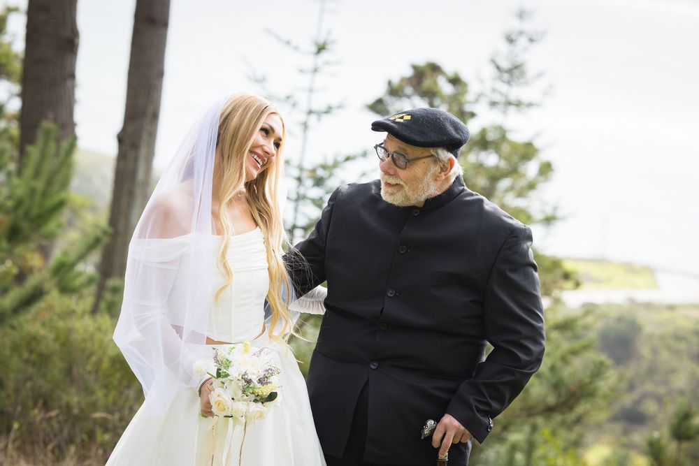 A couple shares a joyful moment together outdoors during a wedding ceremony in a natural setting.