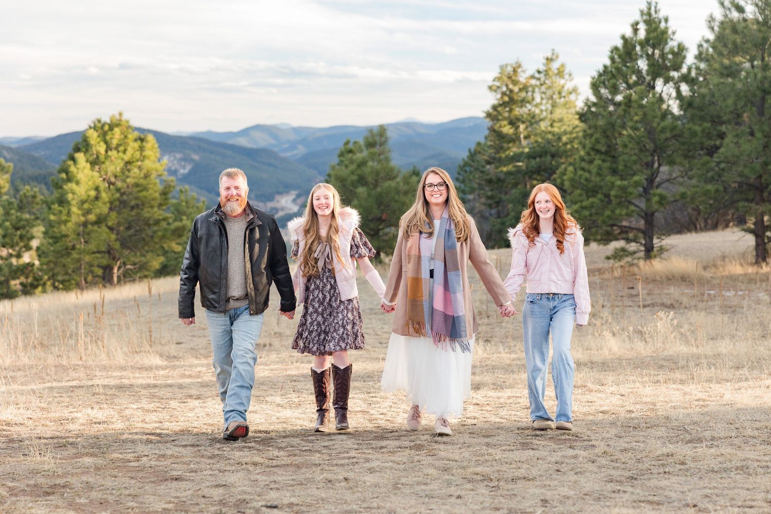 A group walks together across a scenic mountain meadow during golden hour in casual outdoor attire.