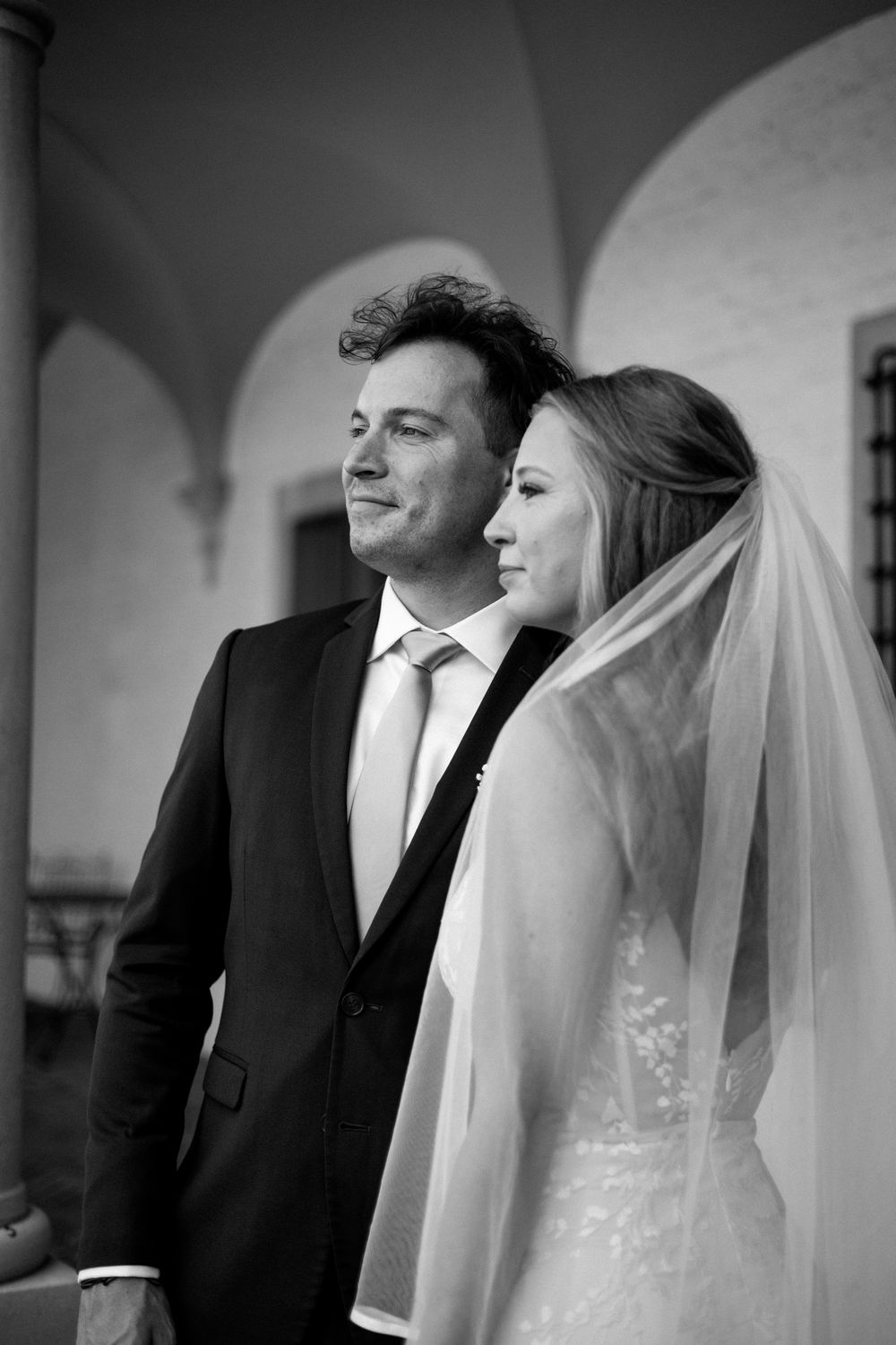Black and white wedding portrait showing profiles of a couple under arched architecture.