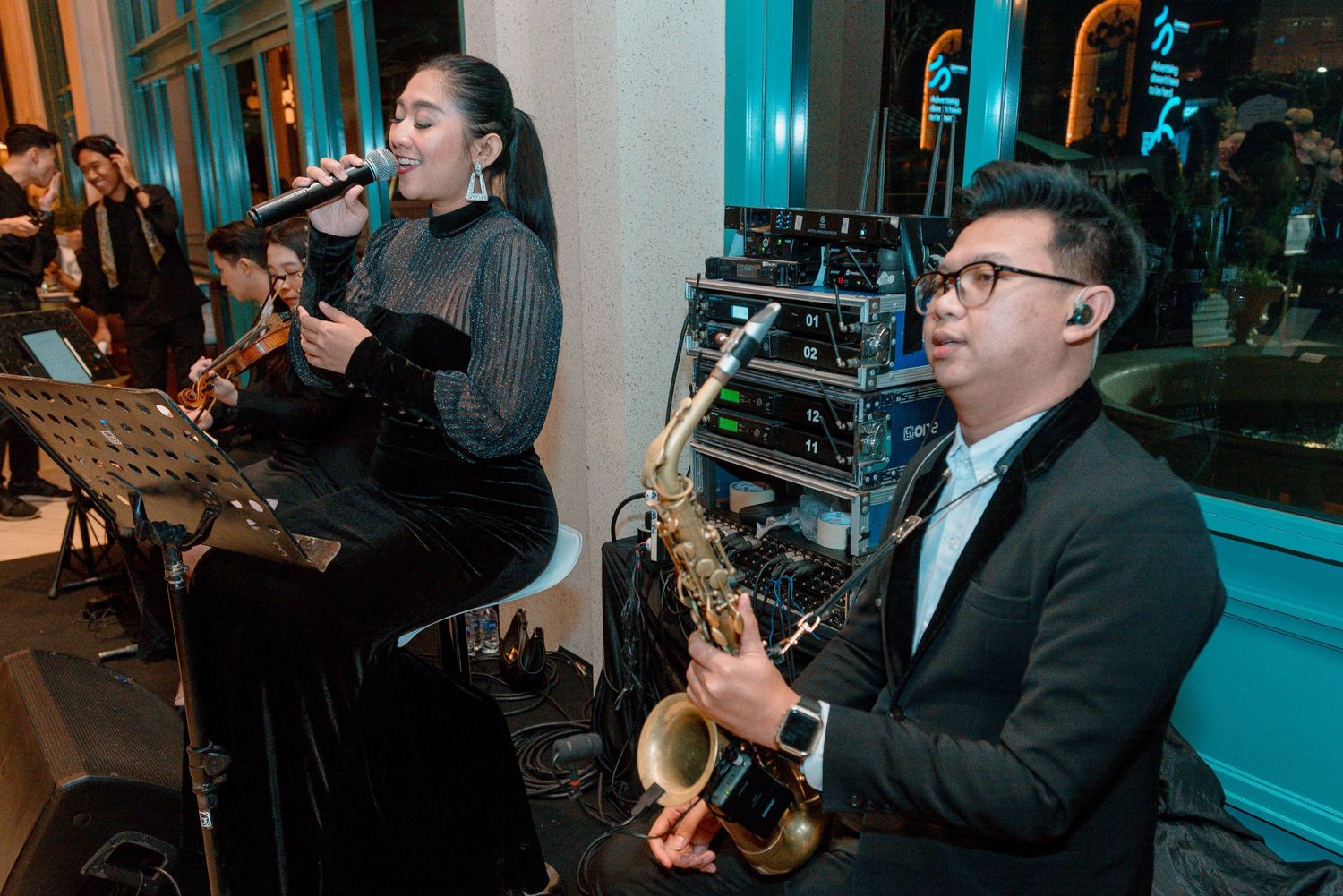 Musicians perform together in a series of concert photos with blue lighting and dark atmospheric ambiance.