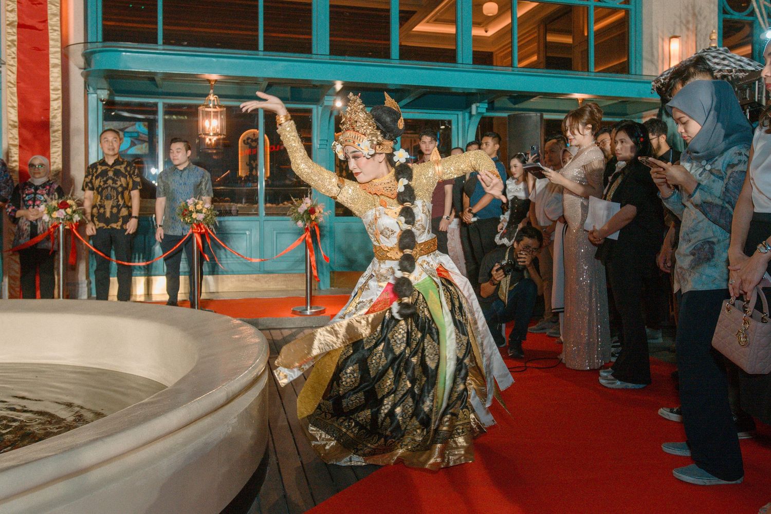 A festive indoor venue with red carpet and decorative lighting hosts a social gathering.