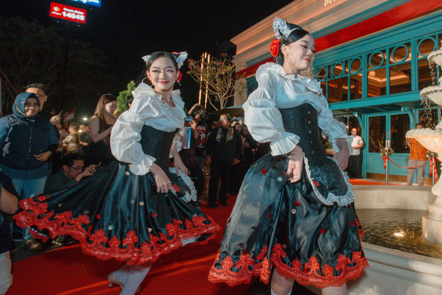 A group performs a traditional folk dance in matching blue and red costumes on a stage.