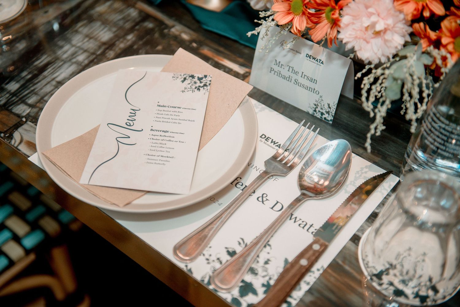 Elegant wedding reception table settings with pink and white stationery, floral centerpieces, and glass decor elements.